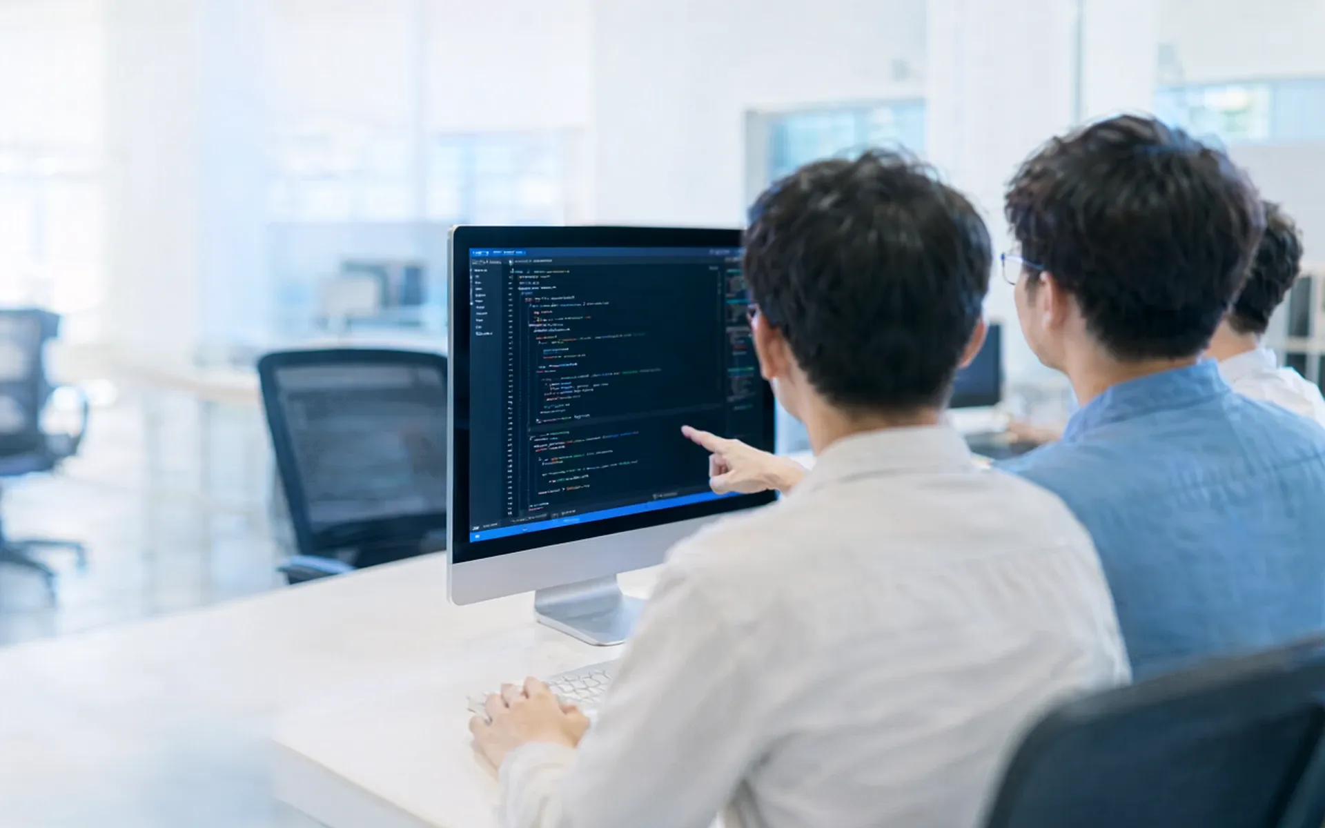 Softwareentwickler arbeiten gemeinsam an einem Bildschirm mit Programmcode