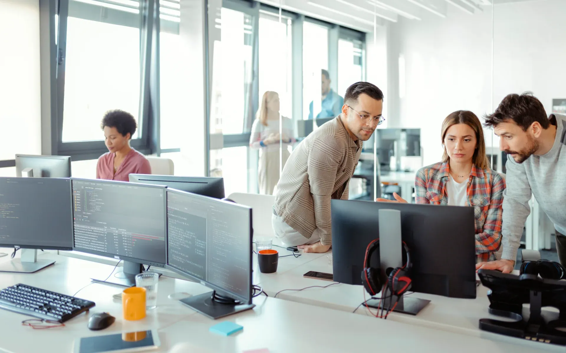 Development team working together at several screens in an office